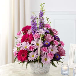 Pink and purple mixed flower arrangement in a white basket