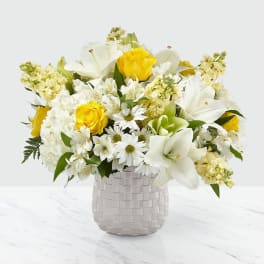 White and yellow mixed flower arrangement in a woven vase