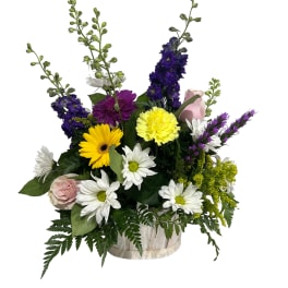Mixed bouquet of daisies, roses, and purple blooms in a clear vase