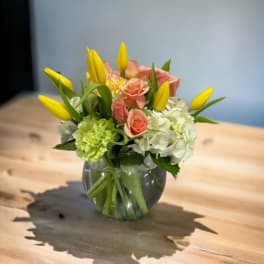 Pink roses and yellow tulips in a clear glass vase