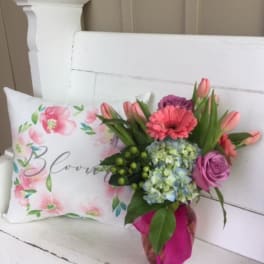 Bouquet with pink tulips, roses, and hydrangea beside a floral pillow