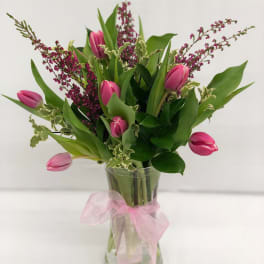 Pink tulips in a clear glass vase with a pink ribbon