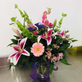 Mixed bouquet in a glass vase with pink lilies and a pink daisy