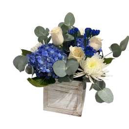 Blue hydrangeas and white roses in a rustic wooden box