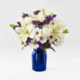 White lilies, daisies, and roses in a blue vase