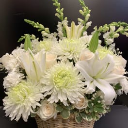 White lilies and chrysanthemums arranged in a wicker basket