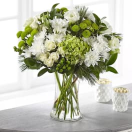 White and green floral arrangement in a clear glass vase