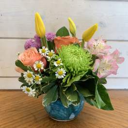 Colorful mixed flower arrangement in a blue vase
