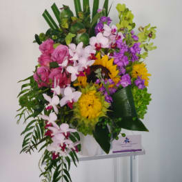 Tall mixed bouquet with sunflowers, pink roses, and orchids in a white vase