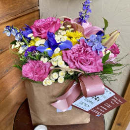 Mixed bouquet in a kraft paper bag with pink ribbon