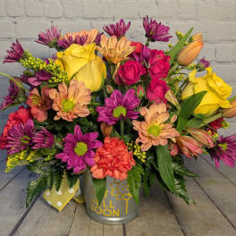 Colorful mixed bouquet in a metal container with yellow roses and purple daisies.