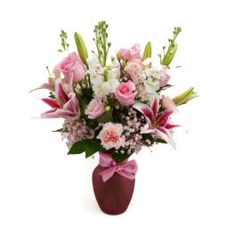 Pink and white mixed flower arrangement in a burgundy vase with a pink ribbon
