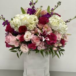 Pink and white floral arrangement in a white hat box