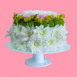 White and green floral arrangement on a pedestal stand with ribbon bows