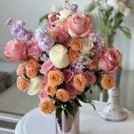 Bouquet of pink, peach, and white roses in a metallic vase