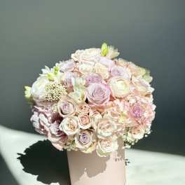 Round pastel bouquet of roses and ranunculus in a blush box