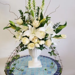 White lilies and cream roses in a white pedestal vase
