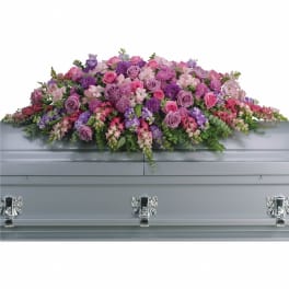 Large pink and purple casket spray of mixed flowers on a silver casket