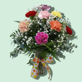 Mixed carnation bouquet in a glass vase with a polka-dot ribbon