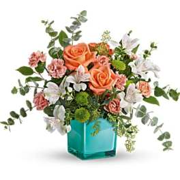 Peach roses and pink carnations in a turquoise glass vase