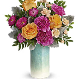 Arrangement of yellow roses and purple carnations in a tall blue and white ceramic vase