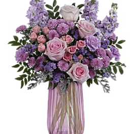 Pink and lavender floral arrangement in a pink glass vase