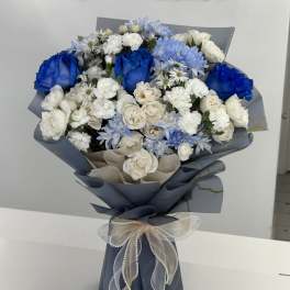 Blue and white bouquet of roses and daisies wrapped in dark paper