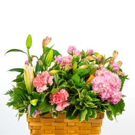 Pink flowers and lilies arranged in a woven basket