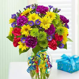 Colorful mixed bouquet in a glass vase with curly ribbon