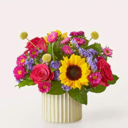 Mixed bouquet with sunflowers, roses, and purple flowers in a striped vase