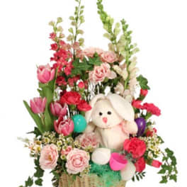 Basket arrangement with pink flowers and a plush bunny