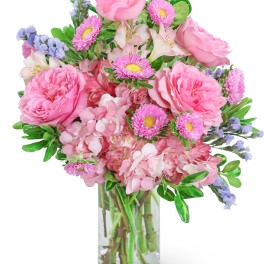 Pink mixed flower arrangement with roses, hydrangeas, and asters in a clear glass cylinder vase