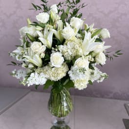 White roses and lilies arranged in a clear glass vase
