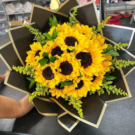 Bouquet of yellow sunflowers wrapped in black paper with gold trim
