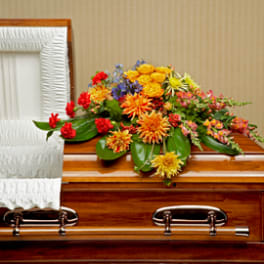 Colorful floral spray on a wooden casket beside a white interior lining