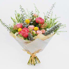 Bouquet of pink peonies and yellow billy balls wrapped in white paper