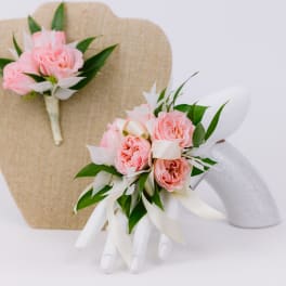 Pink rose boutonnieres with white ribbon on display stands