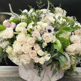 Large white and blush rose arrangement in a marble-patterned vase