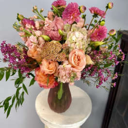 Bouquet of peach and pink flowers in a brown vase