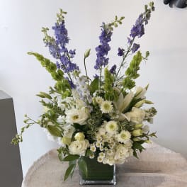 White and purple floral arrangement in a square glass vase
