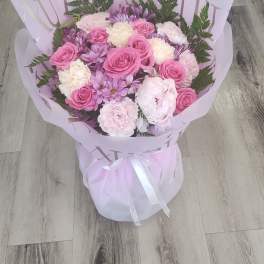 Pink and lavender bouquet with roses and carnations wrapped in pale paper