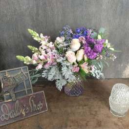 Mixed bouquet of purple, pink, and white flowers in a glass vase