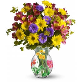 Mixed bouquet of yellow daisies, purple asters, and pink alstroemeria in a clear painted glass vase