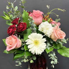 Mixed roses and a white gerbera daisy in a dark glass vase