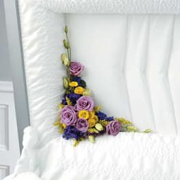 Purple roses and yellow flowers arranged on a white bedspread