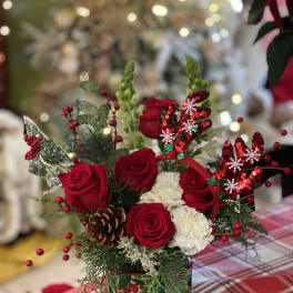 Red roses and white carnations in a glass vase with holiday decorations