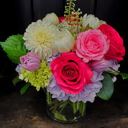 Mixed bouquet of pink, white, and lavender flowers in a glass vase