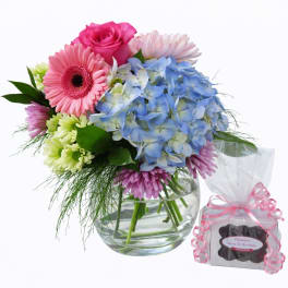 Mixed bouquet in a glass vase with pink, blue, and green flowers