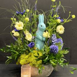 Spring floral arrangement with a blue bunny figurine and a small candle holder