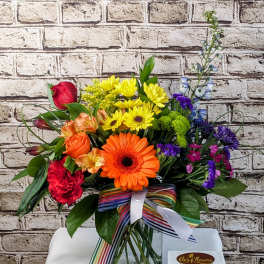 Colorful mixed bouquet in a glass vase with a striped ribbon